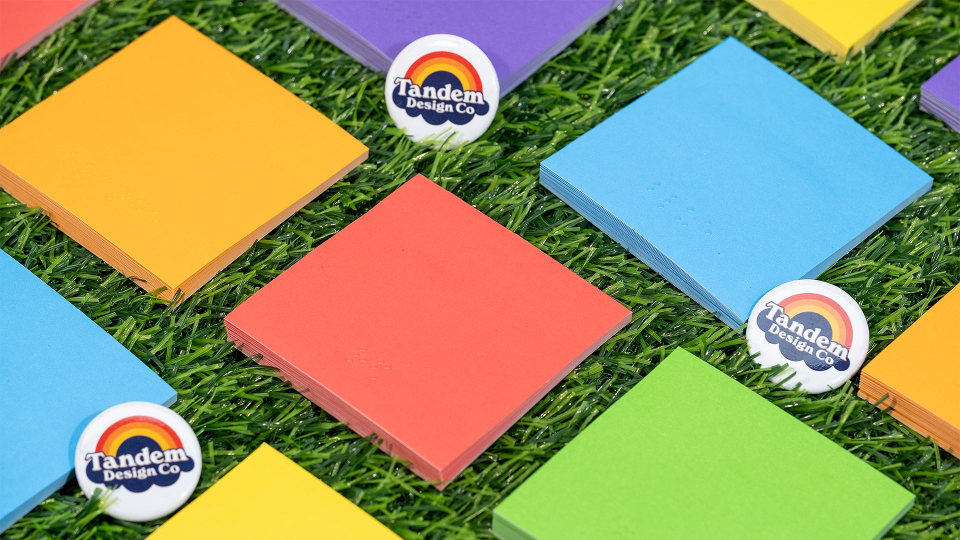 45 degree grid of assorted Braille sticky notes on fake grass 